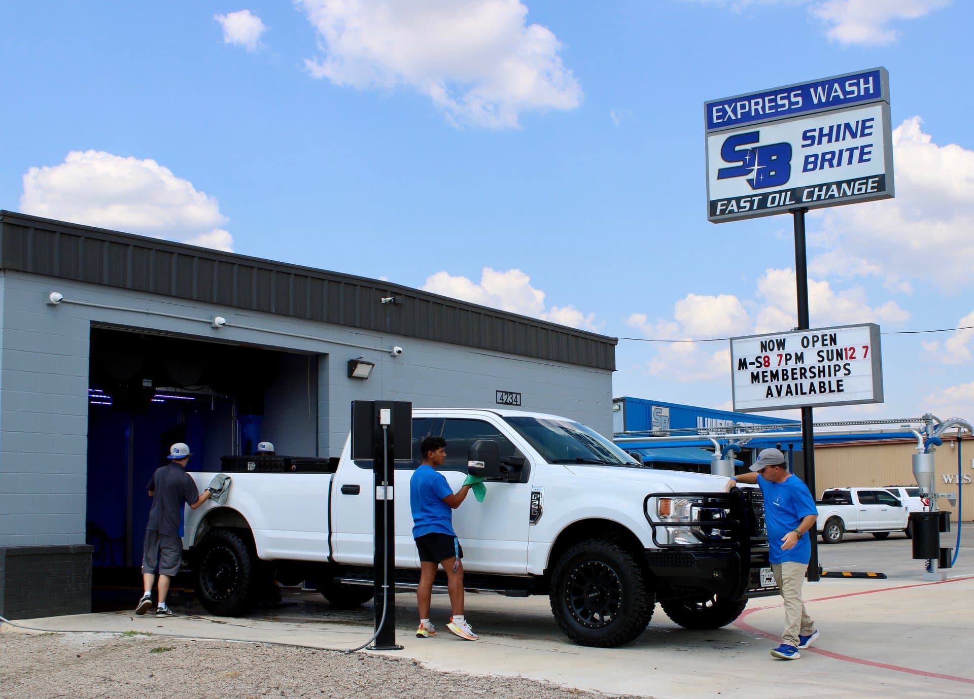 Shine Brite crew towel-drying a white pickup under the canopy at the tunnel exit