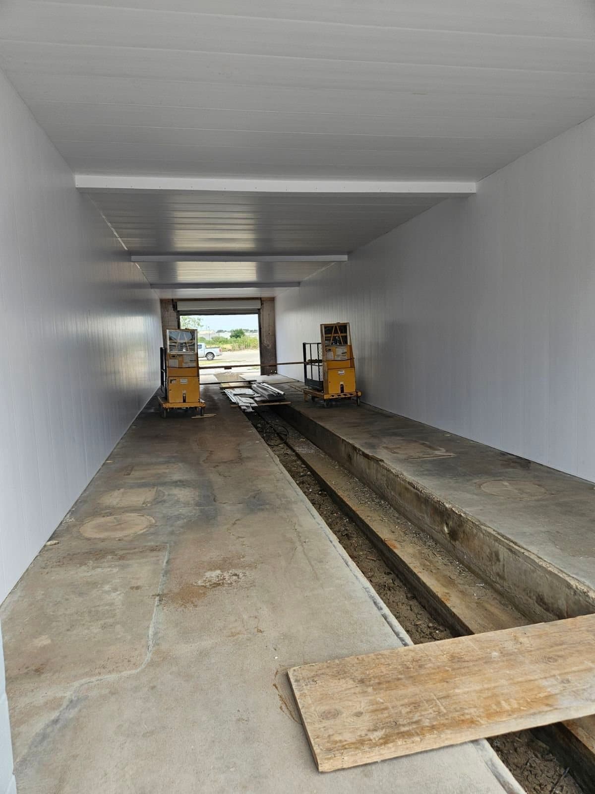 Inside the empty wash tunnel under construction, conveyor trench cut into the floor