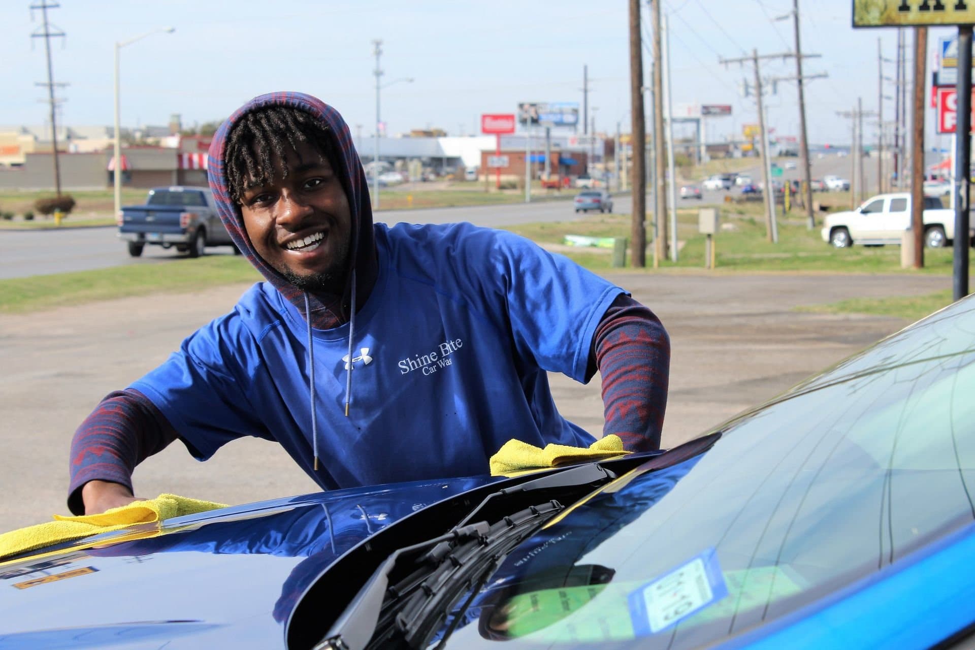 A smiling Shine Brite employee wiping a windshield