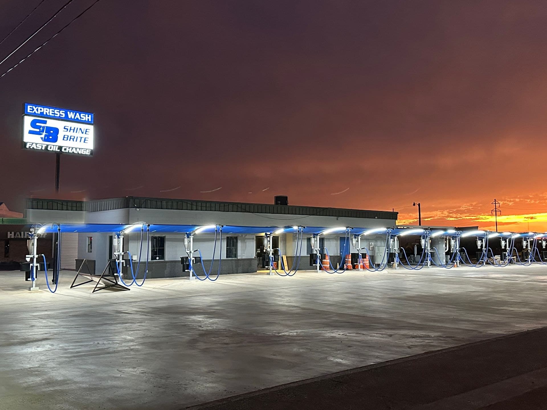 Shine Brite Express Wash on Sherwood Way at dusk: the blue vacuum canopy lit up under an orange sky